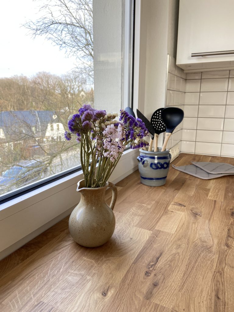 Küchenutensilien und Blumendeko vor dem Küchenfenster